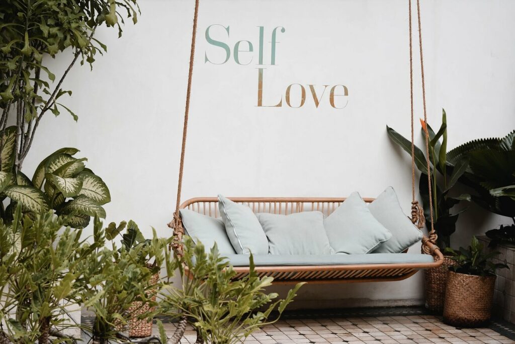Wall with the words painted self-love in a room with a hammock.