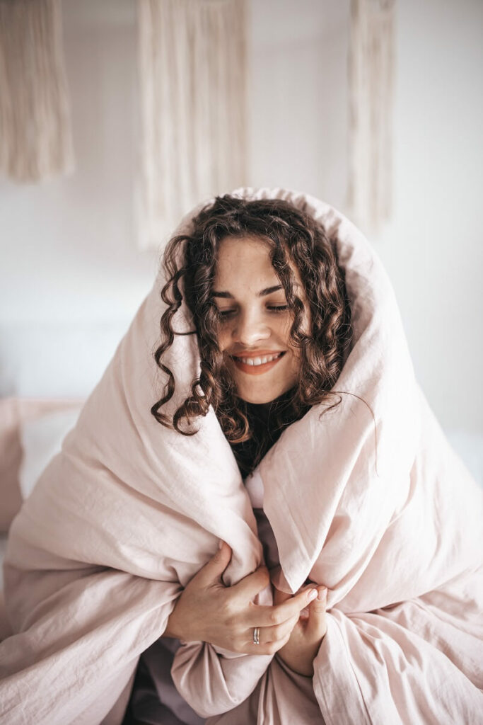 Woman in a cozy big blanket to show self-care ideas for autoimmune disease