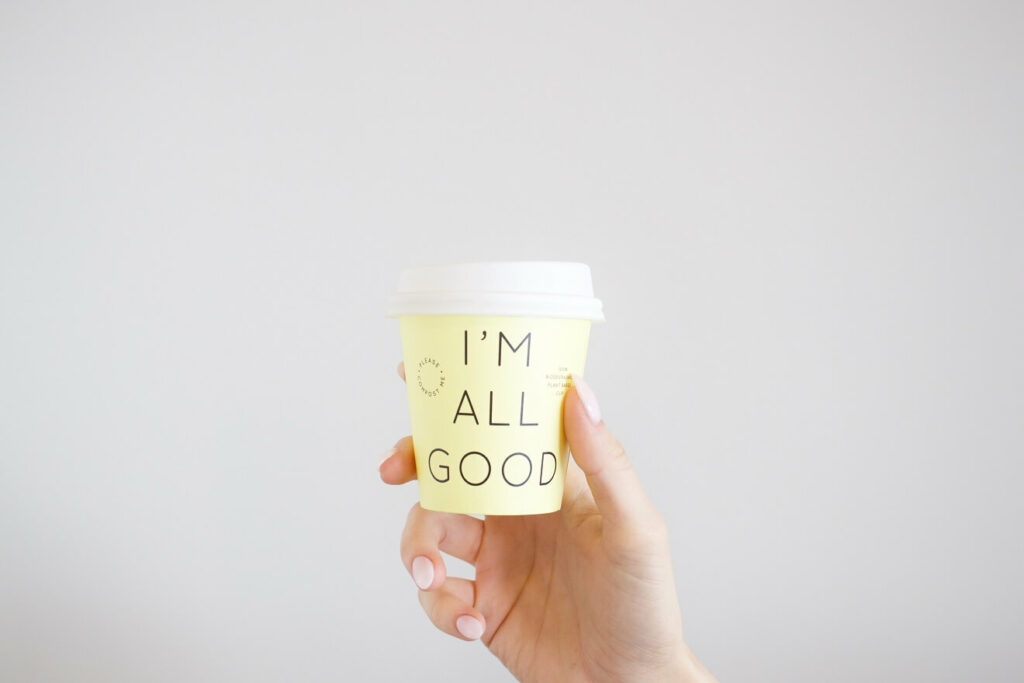 Woman holding a coffee cup that says I'M ALL GOOD for blog post Is spiritual well-being important to your life satisfaction with Chronic Illness?
