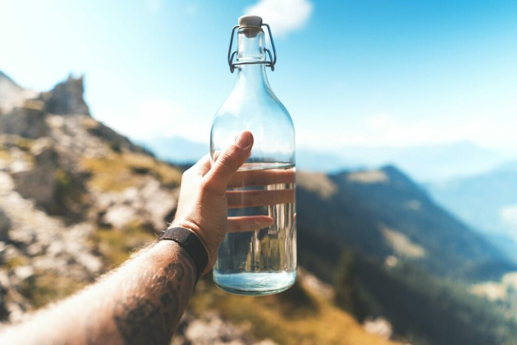 Man holding a water bottle in the sun for blog post The Lifelong Health Benefits Of Drinking Water